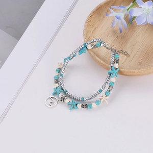 Détail d'un bracelet de cheville boho avec perles d'étoile de mer et pendentif vague