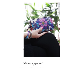 Detailed view of large capacity floral hand clutch with three zippers and wristlet strap