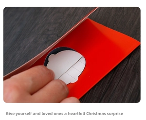 Detail of red 3D Christmas card with hollow wings design on dark wood table