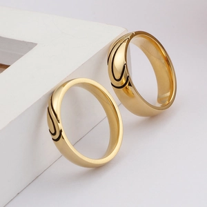 Gold-toned titanium steel couple rings with black curved accents on white display