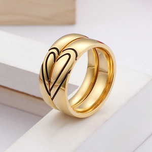 Polished gold stainless steel couple rings with interlocking heart design on white plinth