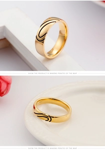 Detail of gold heart engraved ring with black accents on polished stainless steel band