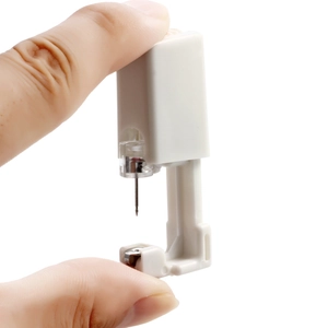 Close-up of a white disposable ear piercing gun held by fingers for easy use