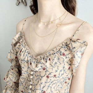 Detail of layered gold 925 silver necklace with mini cross and interlocking rings