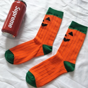 Detail of Halloween pumpkin socks with orange body, green accents, and black stripes