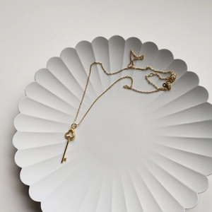 Golden 925 sterling silver necklace with a clover key design pendant on a white tray