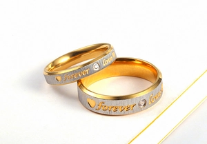 Detail of couple rings with forever love engraving, heart pattern and a small diamond