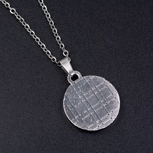 Detailed view of silver Tai Chi pendant back with grid texture on stainless steel O-chain