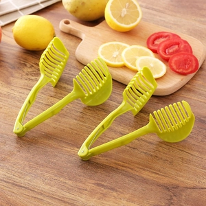 Green handheld tomato and lemon slicer holder tool for uniform fruit and vegetable cutting
