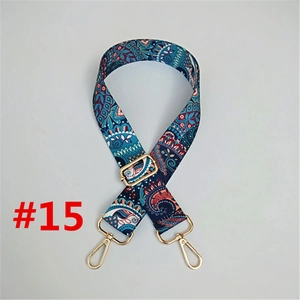 Detail view of ethnic paisley fabric bag strap with golden metal snap hooks and buckles