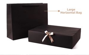 Large horizontal black gift box set with a champagne gold satin bow and matching paper bag