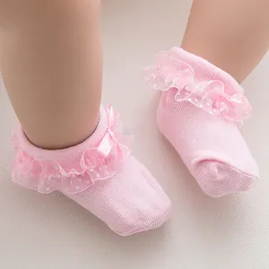 Close-up of pink baby knit socks with white polka dot lace and a satin bow detail