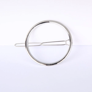 Detailed view of a silver minimalist circular metal hair clip with a smooth polished finish