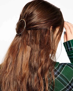 Detail of round golden geometric hair clip styled on a model's half-up hairstyle