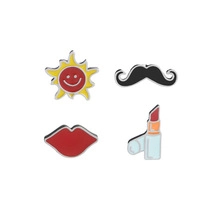 Detail shot of four enamel pins featuring sun, mustache, lips, and lipstick designs