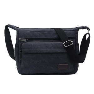 Close-up of black canvas chest bag featuring front zipper pocket and adjustable strap