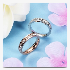 Detail of silver and rose gold stainless steel rings with clear crystals on blue floral background