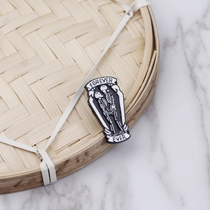 Detail view of Skelton coffin enamel brooch with Forever Ever text on bamboo background