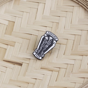 Detailed close-up of coffin enamel pin with skeletons and FOREVER EVER text on bamboo