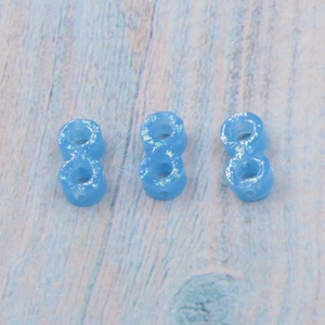 Three blue shimmering infinite opal beads for DIY pendants on light textured background