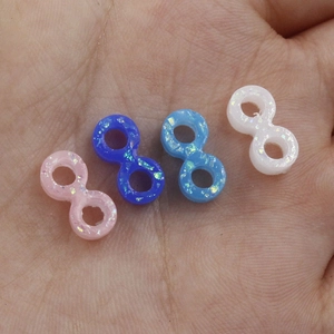 Handheld view of infinite-shaped opal beads in pink, blue, and white with holographic finish
