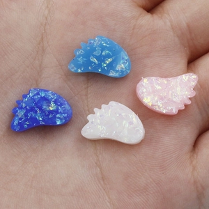 Detail of synthetic opal angel wing beads held to show size and iridescent finish