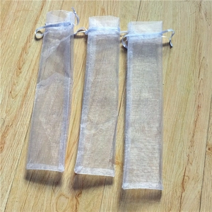 White organza drawstring bags for folding fans or pens on a wood background
