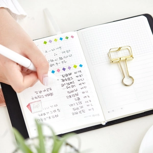 Minimalist faux leather daily planner with snap closure and grid pages showing day plan