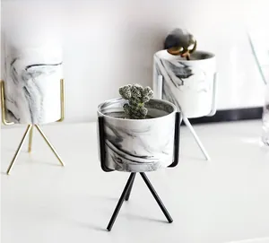 Detail of marble pattern ceramic planters with gold, black, and white metal tripod stands