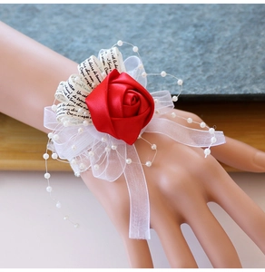 Détail d'un bracelet de fleurs en satin rouge avec rubans imprimés et perles élégantes