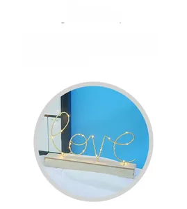 Nahaufnahme der nordischen LED-Buchstabenleuchte Love in Champagner-Gold auf Holzsockel