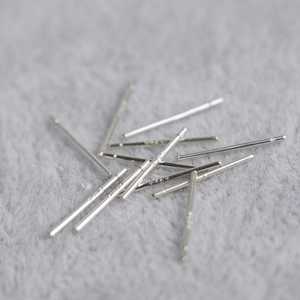 Pile of S925 sterling silver ear pins with visible authenticity hallmark on grey fabric