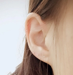 Détail de quatre puces d'oreilles minimalistes en argent sur le lobe et le cartilage