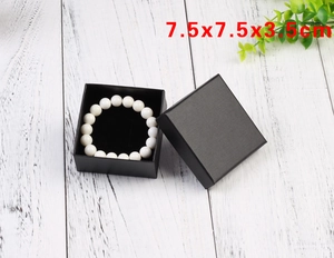 Top view of a 7.5x7.5x3.5cm black jewelry box with a pearl bracelet on a wood surface
