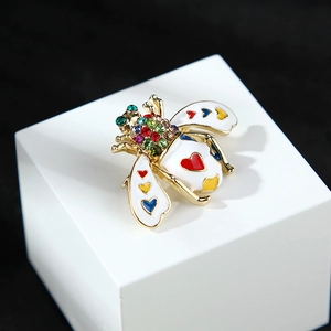 Macro shot of bee brooch with colorful crystals and enamel heart patterns on gold metal
