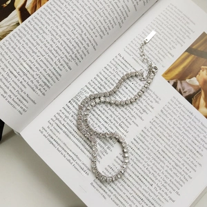 Dettaglio di un girocollo tennis in argento con zirconi appoggiato su un libro