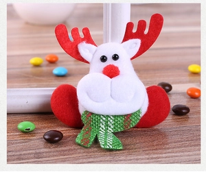 Close-up of a plush reindeer ornament with red antlers and a green glitter scarf on wood