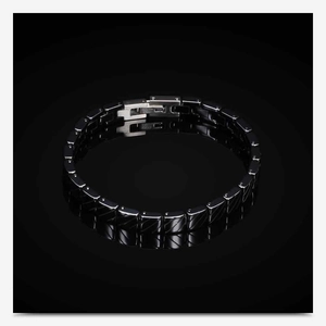 Detail of black ceramic chain bracelet with engraved stainless steel clasp on reflective background