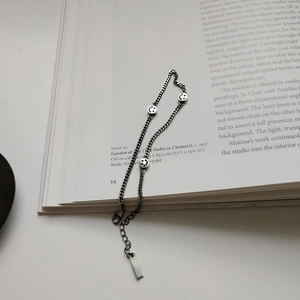 Artistic close-up of a silver chain anklet with smiley face charms on vintage book pages