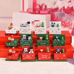 Three wooden Christmas train ornaments in white green and red on festive gift boxes
