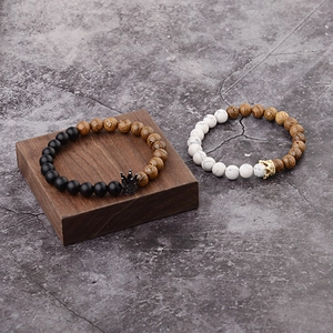 Detail of beaded bracelets with crown charms and wood texture on a stone background