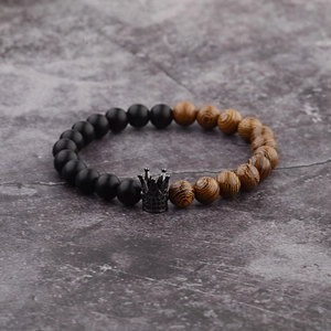 Macro view of beaded bracelet with black matte beads, wood grain beads and crown charm