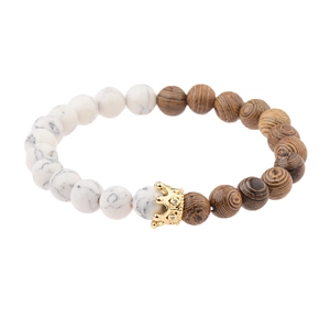 Close-up of beaded bracelet featuring white turquoise, wood grains, and a gold crown charm