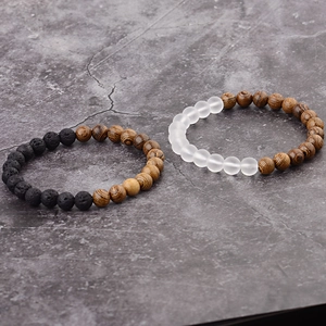 Close-up of black volcanic rock and brown wood beads on minimalist beaded bracelets
