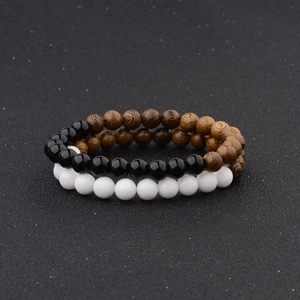 Detail of double-layer beaded bracelets with wooden texture, white stone, and black beads