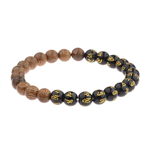 Close-up of wooden and black beads with golden engraved symbols on a stretch bracelet