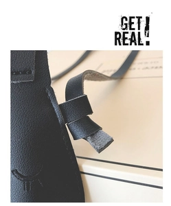 Close-up of black leather child bag featuring delicate closed eye and eyelash embossing