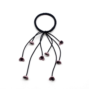 Detail of sweet black braided hair tie with pink flower tassels and matte texture