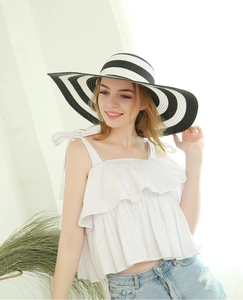 Detail of wide brim straw sun hat with black and white stripes for summer beach outfit