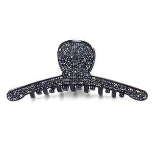 Detail of a navy blue shark hair claw clip encrusted with sparkling rhinestones on white